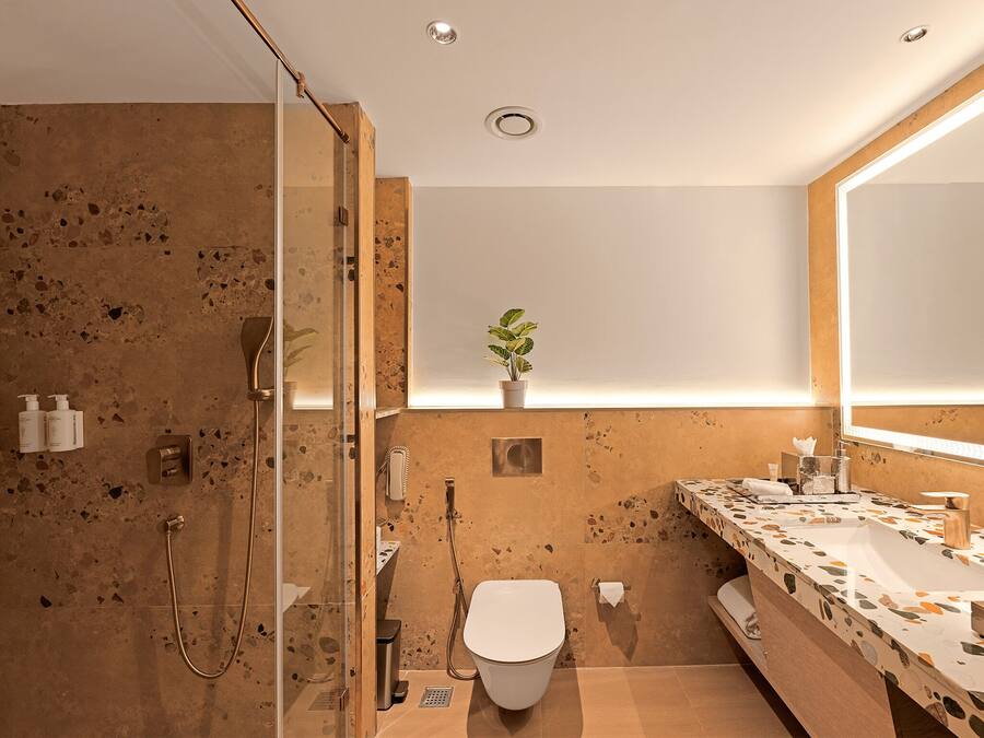 Un baño moderno con cabina de ducha de vidrio, inodoro independiente y tocador con un espejo grande.