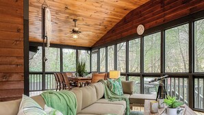 A cozy cabin interior with a wooden ceiling, large windows, a sofa, a dining table, and a telescope. - Creekside Adventure! 10 steps from the cascading and gentle Fightingtown Creek (Blue Ridge)