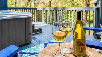 Un bain à remous sur une terrasse, avec une bouteille de vin et deux verres posés sur un dessous de verre.