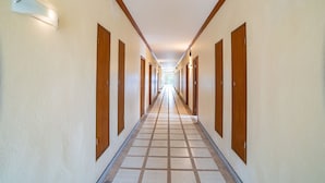 A long, narrow hallway with wooden doors on both sides, leading to individual rooms. - The BRC Ao-nang HOTEL (Krabi)