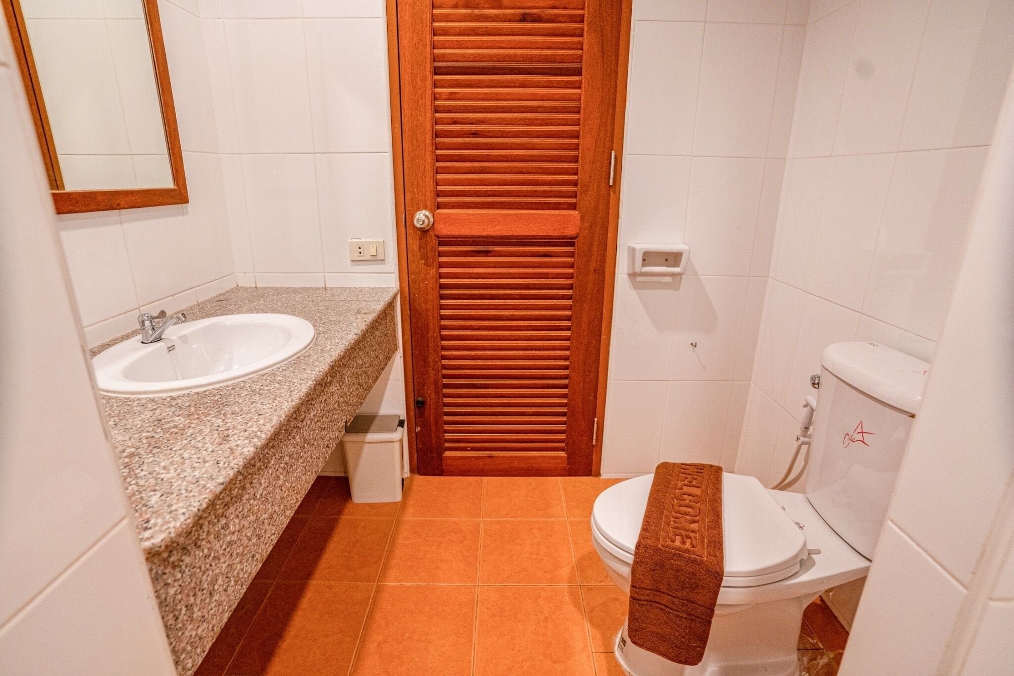A bathroom with a wooden door, a sink, and a toilet.