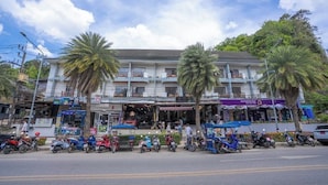 A multi-story building with a restaurant on the ground floor, surrounded by parked motorcycles and palm trees. - The BRC Ao-nang HOTEL (Krabi)