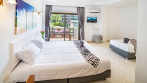 A hotel room with a large bed, a smaller bed, a TV, and a balcony with a view of buildings. - The BRC Ao-nang HOTEL (Krabi)