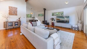 A modern living room with a sofa, a coffee table, a fireplace, and a television.