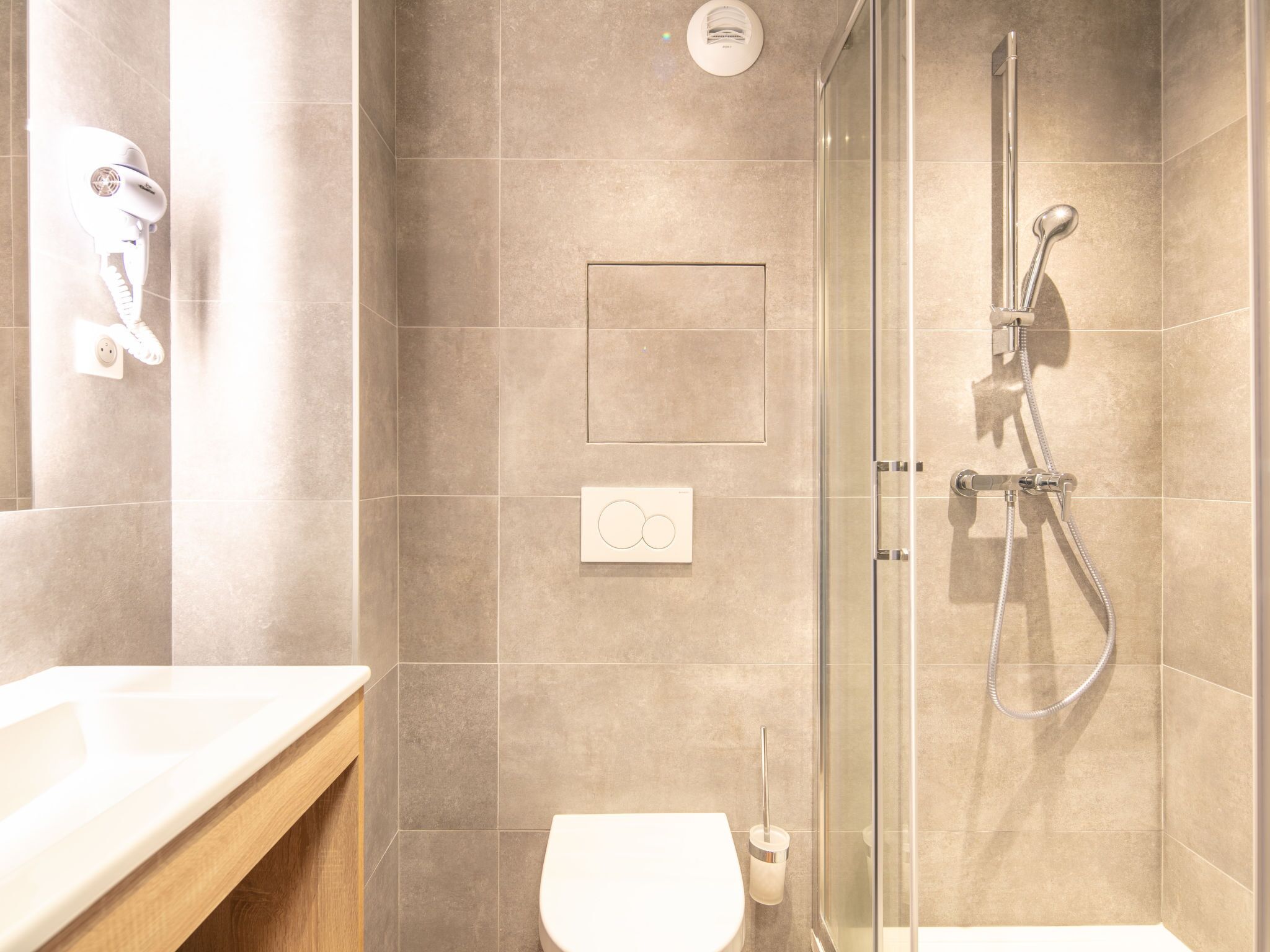 A modern bathroom with a glass-enclosed shower, a toilet, and a vanity with a mirror.