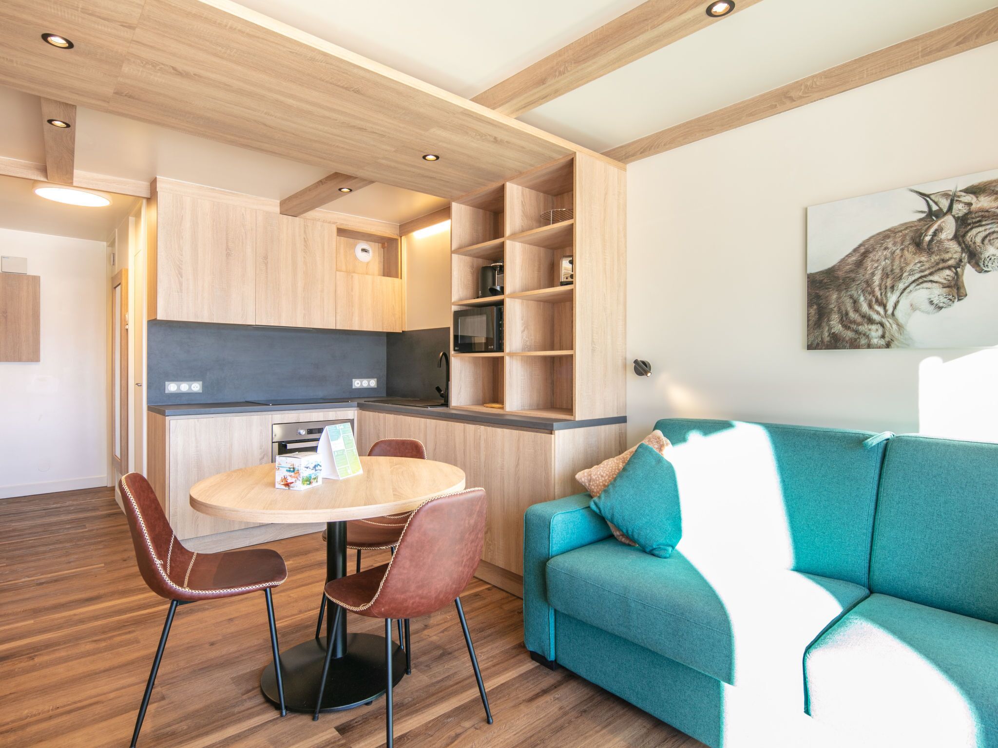 Una cocina moderna con armarios de madera, un microondas integrado y un comedor con una mesa y sillas redondas.