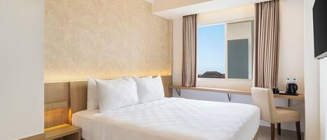Una camera d'hotel con un letto grande, una scrivania con una sedia, una finestra con tende e una televisione appesa al muro.