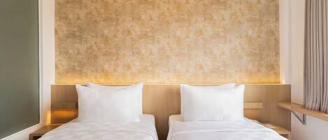 Habitación de hotel con dos camas, una pared con textura y un cabecero de madera.