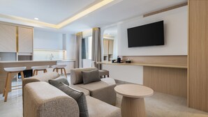 Een moderne woonkamer met een bank, een salontafel en een aan de muur bevestigde televisie.