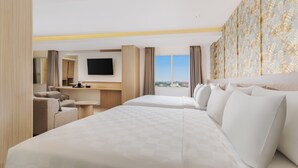 Een hotelkamer met twee bedden, een televisie, een bureau en uitzicht op de stad.