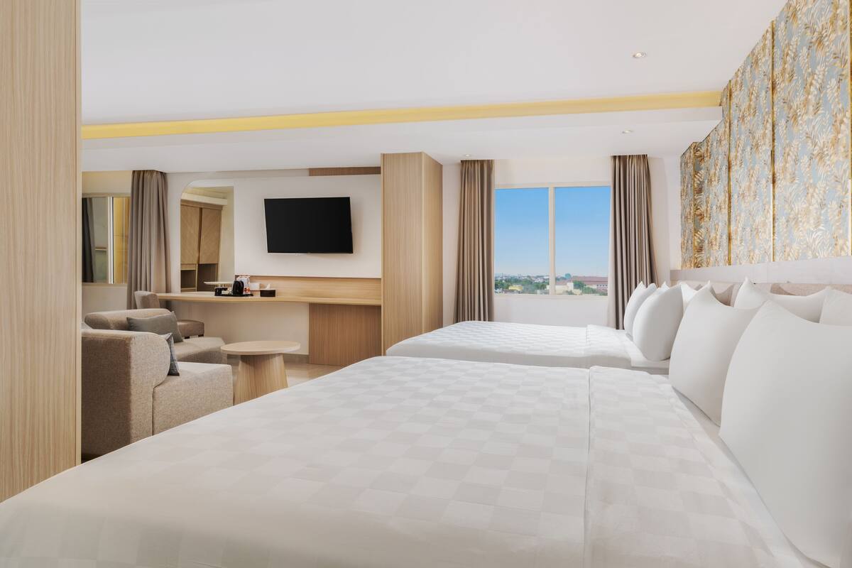 Ein Hotelzimmer mit zwei Betten, einem Fernseher, einem Schreibtisch und Blick auf die Stadt.