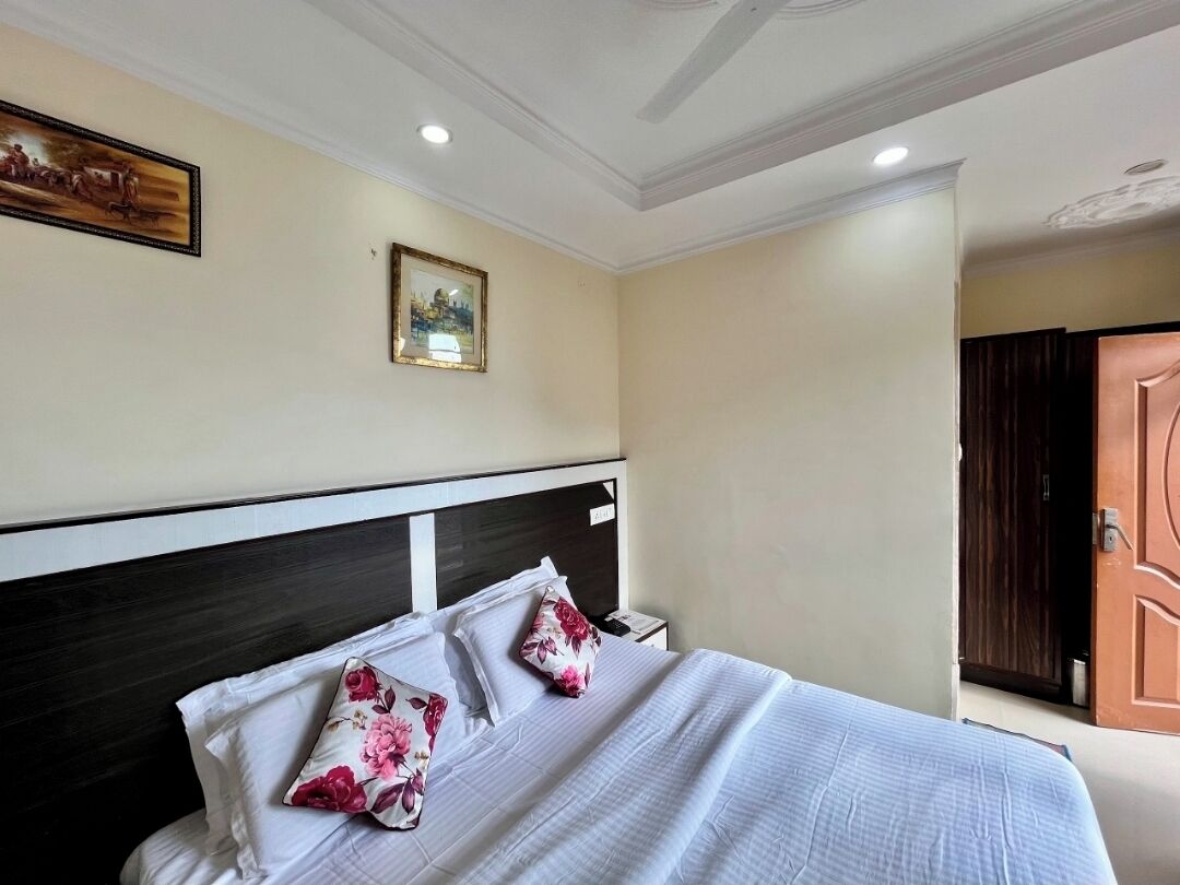 A hotel room with a bed, a nightstand, a framed picture on the wall, and a door.