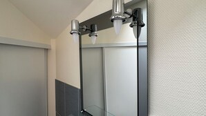 Une salle de bain moderne avec un grand miroir, des carreaux de couleur sombre et une cabine de douche en verre.