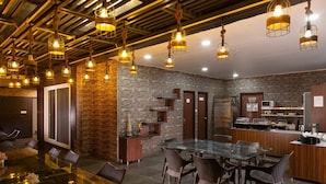 A restaurant with a glass dining table, wicker chairs, and hanging light fixtures. - Hotel Park Royale Inn (Dehradun)