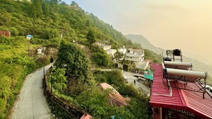 A hillside village with a winding road, buildings, and a red-roofed structure. - Hotel Park Royale Inn (Dehradun)