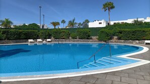 A clear blue swimming pool with steps leading into it, surrounded by a stone wall and palm trees. - Playa D Las Américas-casa Rucaba (Adeje)
