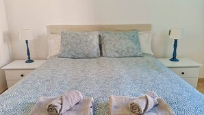 A neatly made bed with patterned bedding and two towels folded at the foot of the bed. - Playa D Las Américas-casa Rucaba (Adeje)