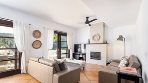 A modern living room with a sofa, a TV, and a fireplace. - El Casar Townhouse Benahavis (Benahavis)