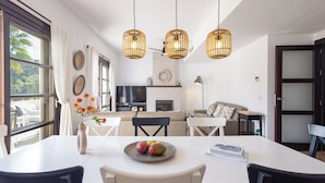 A modern kitchen with a dining area, large windows, and hanging pendant lights. - El Casar Townhouse Benahavis (Benahavis)