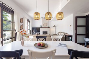 A modern kitchen with a dining area, large windows, and hanging pendant lights. - El Casar Townhouse Benahavis (Benahavis)