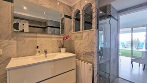 A modern bathroom with a marble vanity, a glass shower enclosure, and a view of the ocean through the glass door. - Apartment Seese Go2lloret (Lloret de Mar)