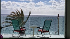 A balcony with two chairs and a small table, overlooking a body of water with a clear sky. - Apartment Seese Go2lloret (Lloret de Mar)