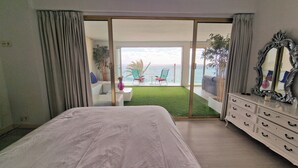A bedroom with a bed, a dresser, and a view of a balcony with chairs and a table. - Apartment Seese Go2lloret (Lloret de Mar)