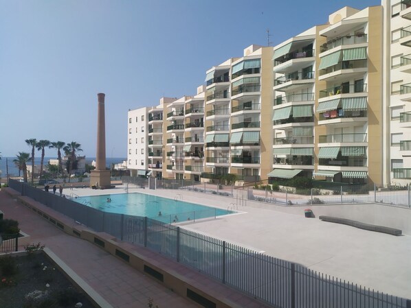 Un hôtel à plusieurs étages doté de balcons, d’une piscine et offrant une vue sur la mer.