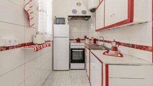 A compact kitchen with white cabinets, a microwave, a stove, and a sink. - Emblematic House in Santa Cruz de La Pal (Santa Cruz de la Palma)