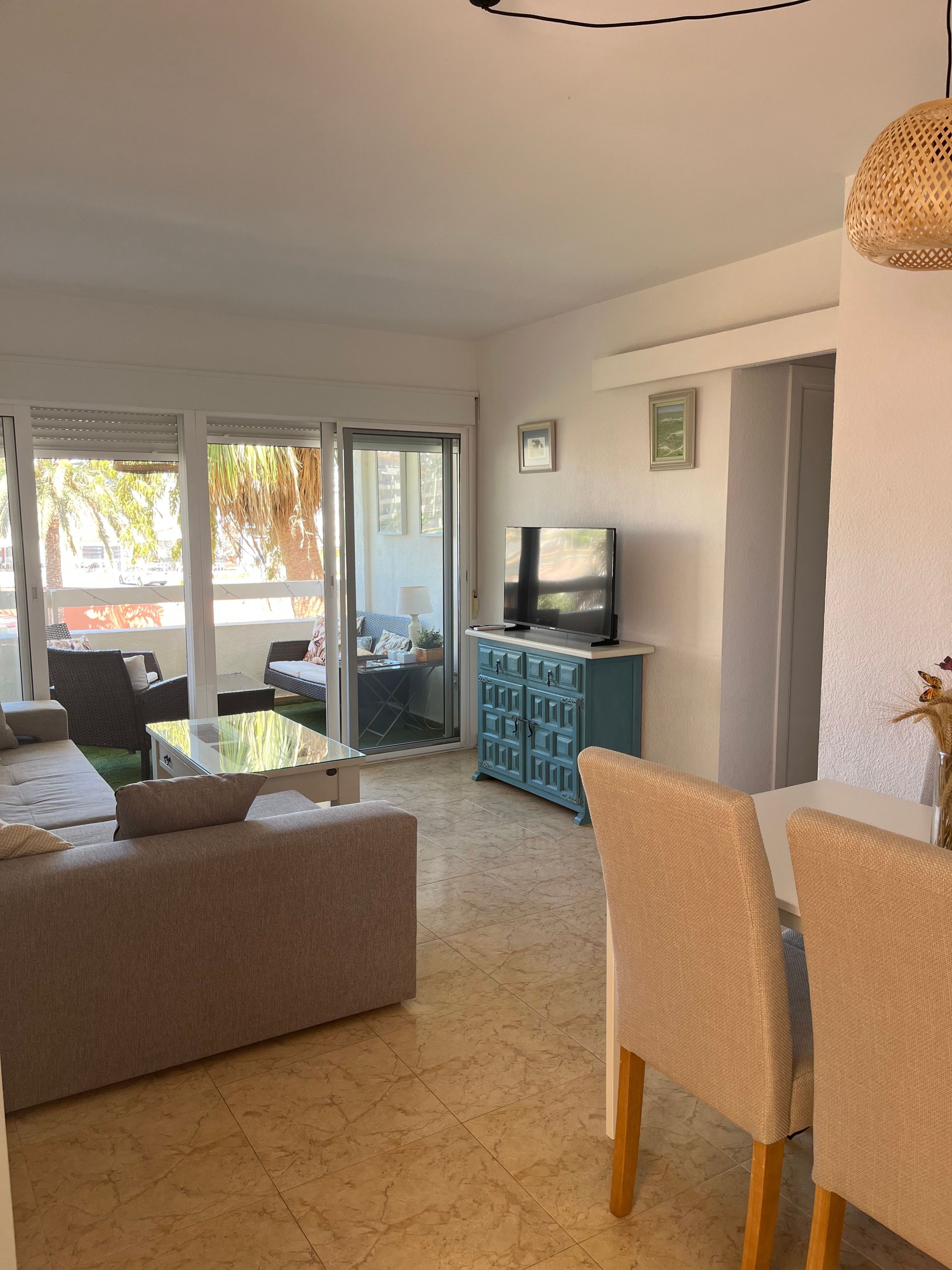 A modern living room with a sofa, a dining table with chairs, a television, and a cabinet.