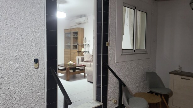 A staircase leading to a living area with a dining table, chairs, and a window. - VAO Holiday Rental-los Narejos by Oasis (Los Alcazares)
