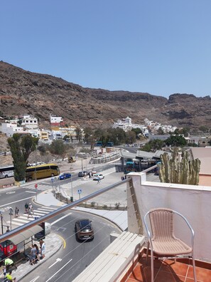 A view of a coastal town with buildings, a road, and a mountain in the background. - 1 Bedroom Apartment in the Center of Puerto de Mogan (Mogan)