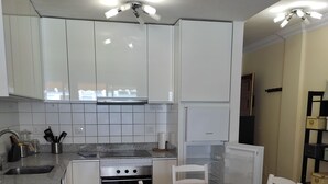 A compact kitchen with white cabinets, a built-in oven, and a dining table with chairs. - 1 Bedroom Apartment in the Center of Puerto de Mogan (Mogan)