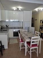 A compact kitchen with white cabinets, a built-in oven, and a dining table with chairs.