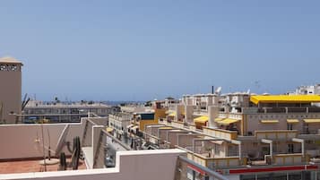 A rooftop terrace with a view of a cityscape, including buildings and a street with cars.