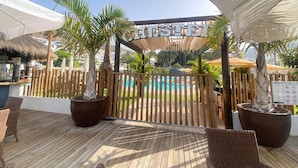Een houten terras met rieten meubilair, een zwembad en een bord met de tekst 'CHESTER'.