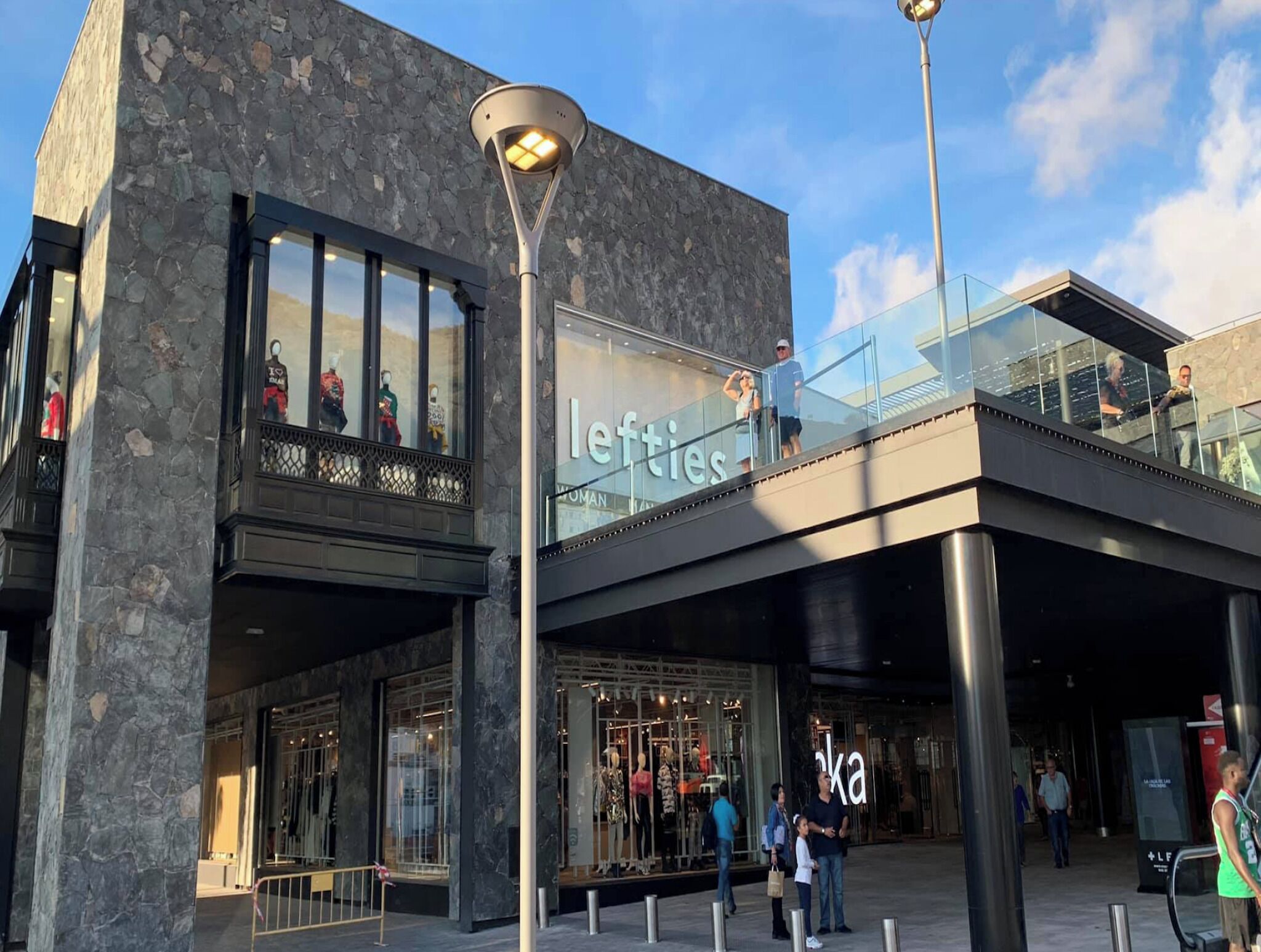A modern building with a stone facade, large glass windows, and a sign for 'lefties'.