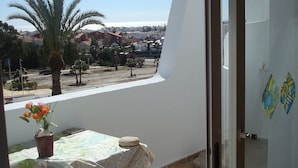A balcony with a table, a potted plant, and a view of a residential area. - Impressive Apartment in Ground Floor With Terrace of 2 Rooms, A A and Pool 4 (Vera)