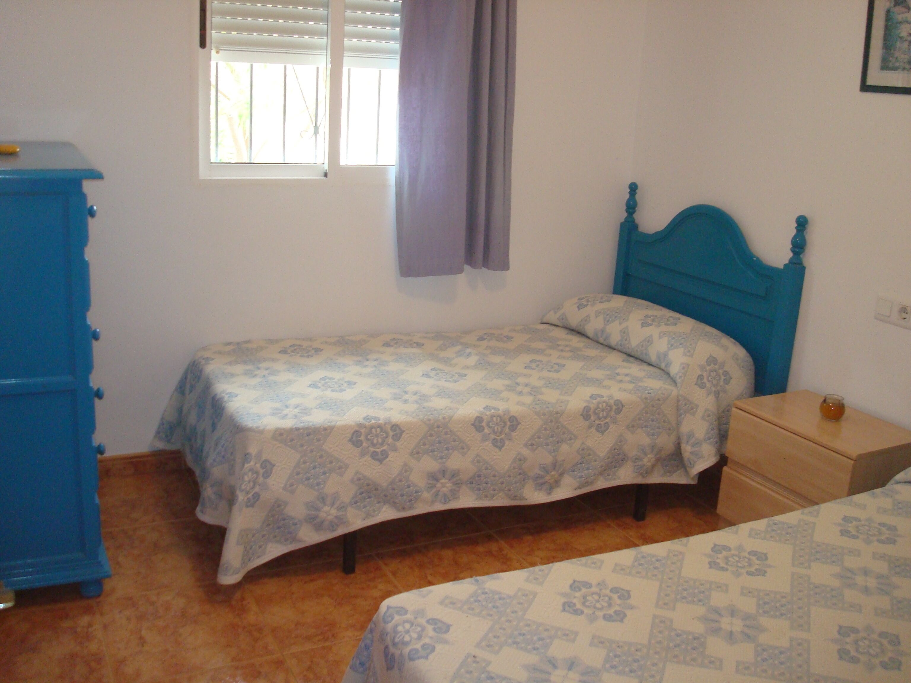 Un dormitorio con dos camas individuales, un aparador y una ventana con persianas.