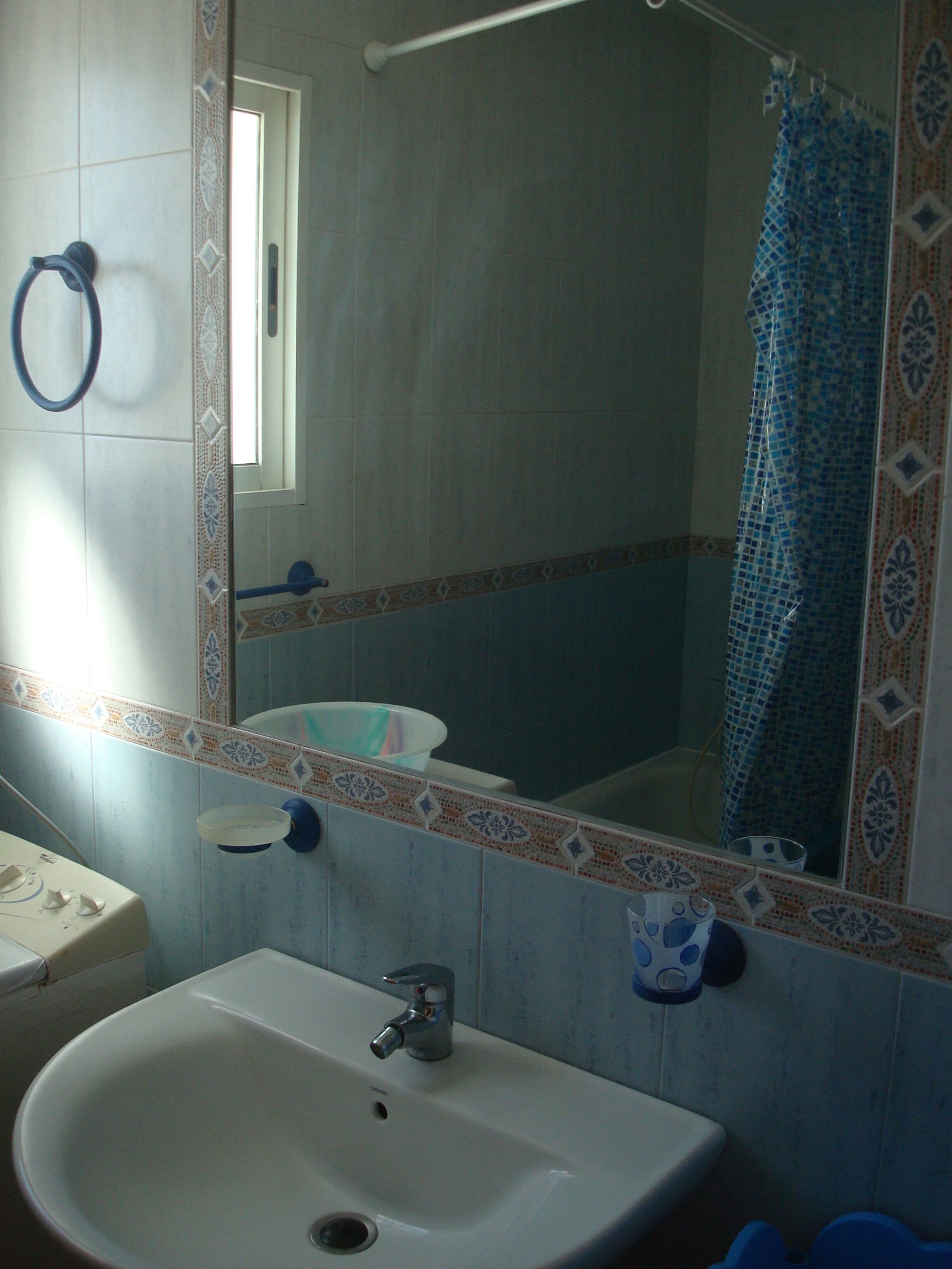 Un baño con lavamanos, espejo y cortina de ducha.