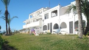A modern building with a white facade, multiple balconies, and a playground area with a slide. - Impressive Apartment With Terrace and two Rooms, AC and Pool (Vera)