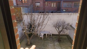 Un piccolo cortile con un tavolo, due sedie, un albero e un muro in mattoni.