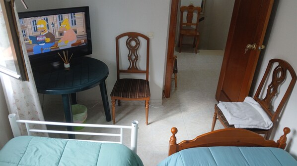 A room with two beds, a television, a wooden chair, and a door. - Room-private Double Room in Toledo (Toledo)