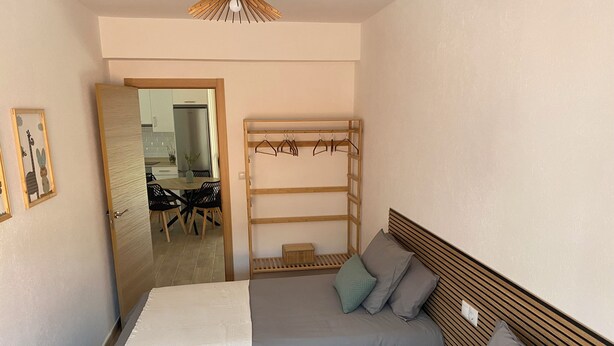 A bedroom with two beds, a wooden headboard, a small wooden shelf, and a door leading to a dining area. - Relax in Comfort at Charming 3-bedroom Vacation Home in Vilar España Carnota (Carnota)