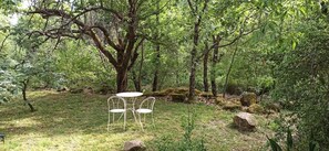 Ένα όμορφο φυσικό περιβάλλον, με ένα τραπέζι και δύο καρέκλες τοποθετημένα κάτω από ένα μεγάλο δέντρο.