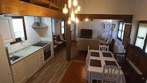 Eine kleine Küche mit Essbereich, Holzbalken und einem Fernseher im Hintergrund.
