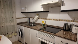 Een keuken met een wasmachine, een spoelbak, een fornuis en een broodrooster.