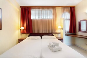 Relax in comfort with a large bed, wooden headboard, and a convenient nightstand with a lamp.