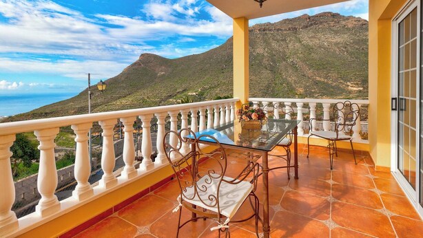 A balcony with a glass table and metal chairs, overlooking a mountainous landscape. - Beautiful Arianny House With Pool (Arona)
