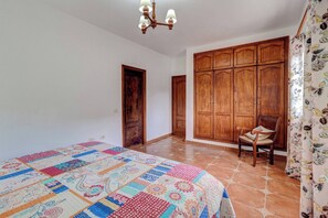 A bedroom with a large bed, wooden wardrobe, and a chair. - Beautiful Arianny House With Pool (Arona)